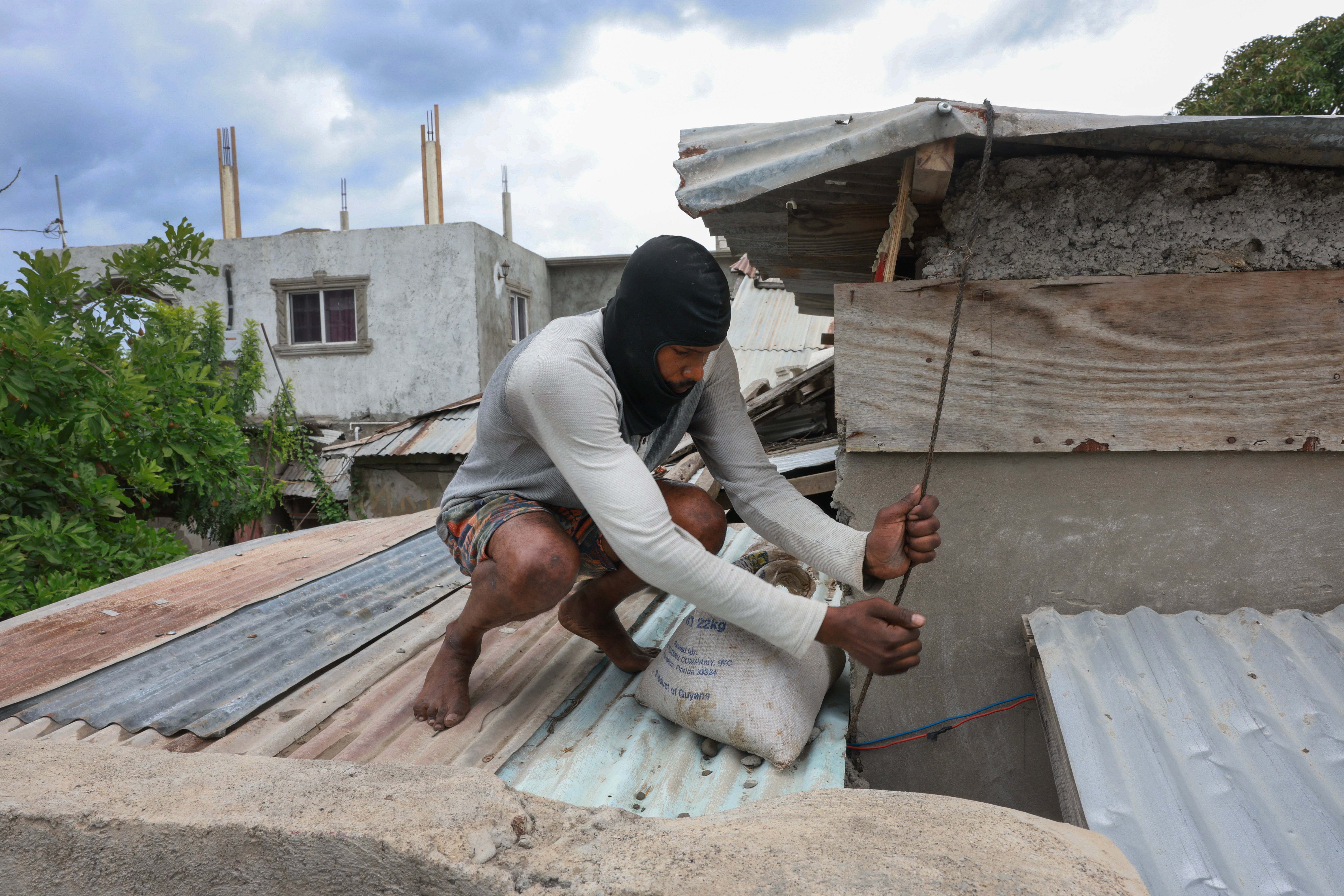 Een persoon plaatst woensdag zandzakken op het dak van een huis in Kingston, Jamaica, terwijl orkaan Beryl nadert